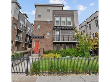Stylish modern townhouse with a brick facade, balcony, a red front door and a well-maintained fenced yard at 1325 Jackson St, Denver, CO 80206