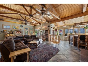 Spacious living room featuring wood-beam ceilings, skylights, tile flooring, and a comfortable leather sofa at 829 Colorado Blvd, Idaho Springs, CO 80452