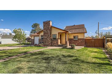 Charming home featuring a brick chimney, well-manicured lawn, and a welcoming front walkway at 5420 E 61St Way, Commerce City, CO 80022