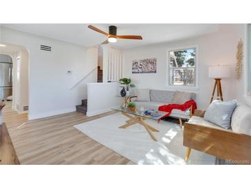 Bright living room featuring a ceiling fan, large window, and modern decor and a set of stairs to the second story at 1601 Robb St, Lakewood, CO 80215