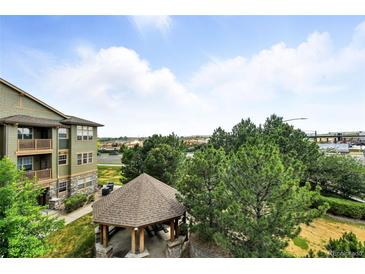 View from the condo balcony of the community gazebo, green space and treeline under a cloudy blue sky at 8489 Canyon Rim Cir # 302, Englewood, CO 80112