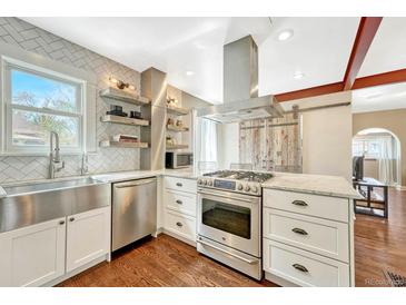 Modern kitchen with stainless steel appliances, floating shelves, white cabinets, and an island with a marble countertop at 4720 W 39Th Ave, Denver, CO 80212