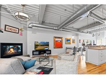 Open living room with fireplace, hardwood floors, exposed ductwork, and modern decor at 1435 Wazee St # 504, Denver, CO 80202