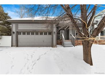 Charming gray home featuring an attached garage and a welcoming front porch, dusted with snow at 2112 Springs Pl, Longmont, CO 80504