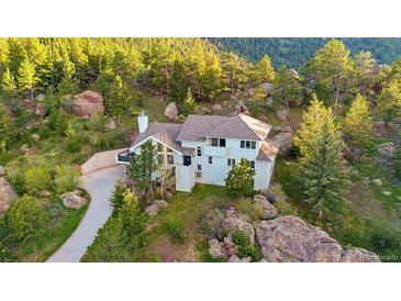 Stunning home nestled in the mountains with mature trees and natural rock landscaping at 9001 Eastridge Rd, Golden, CO 80403