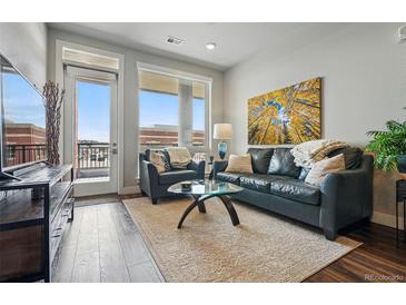Relaxing living room featuring a black leather couch, a plush rug, and sunny balcony access at 20 Wilcox St # 208, Castle Rock, CO 80104