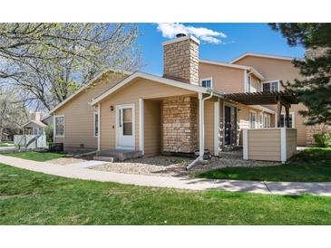 Charming home featuring stone accents on the chimney and porch with a well-maintained lawn and landscaped surroundings at 8422 Everett Way # D, Arvada, CO 80005