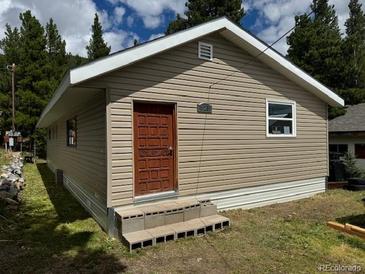 Charming one-story home with light tan siding and a wooded surrounding landscape at 325 Aspen Rd, Idaho Springs, CO 80452