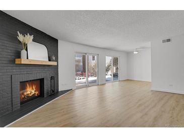 Bright living room with fireplace and sliding glass doors leading to a patio at 3369 S Monaco Street Pkwy # A, Denver, CO 80222