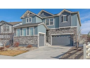 Charming two-story home featuring a combination of stone veneer and blue siding, with a gray two car garage at 27185 E Costilla Dr, Aurora, CO 80016