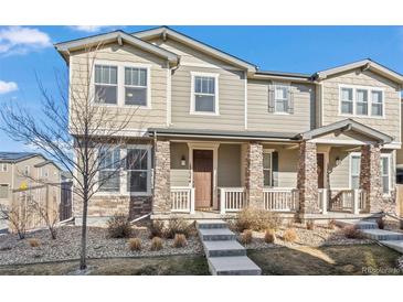 Inviting townhouse with stone accents, covered porch, and landscaped front yard at 13734 Ash Cir, Brighton, CO 80602