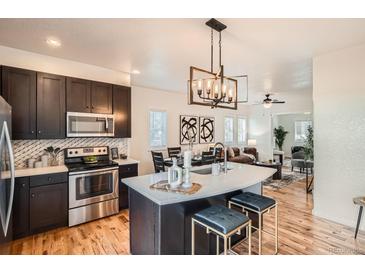 Modern kitchen featuring stainless steel appliances, an island with seating, and stylish light fixtures at 2426 S Acoma St, Denver, CO 80223