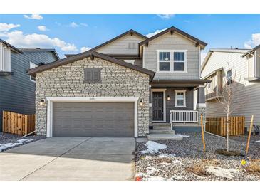 Two-story home with stone and siding exterior, gray garage door, and small front porch at 13372 E 110Th Way, Commerce City, CO 80022