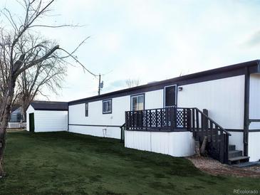 Mobile home exterior with detached garage and grassy yard at 102 Jackson Dr, Firestone, CO 80520