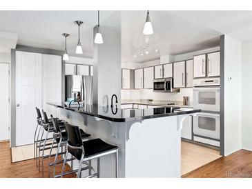 Modern kitchen features a black countertop island with seating and pendant lighting above at 3131 E Alameda Ave # 803, Denver, CO 80209