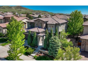 Beautiful two-story home with a stone and stucco facade, well-manicured landscaping, and a tile roof at 15235 W Iliff Ave, Lakewood, CO 80228