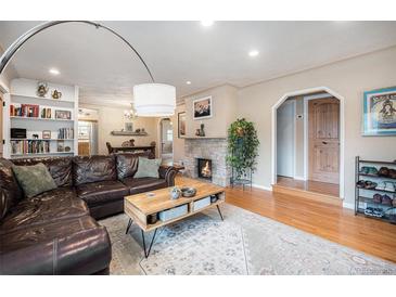 Inviting living room featuring a stone fireplace, hardwood floors, and a comfortable leather sofa at 895 Vance St, Lakewood, CO 80214