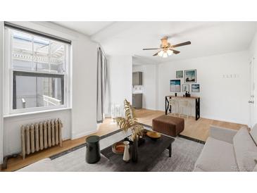 Bright living room featuring a ceiling fan, stylish decor, and a breakfast bar with sleek counter stools at 215 E 11Th Ave # D5, Denver, CO 80203