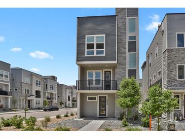 Modern gray three-story home with stone accents and a small balcony at 20999 E Quincy Dr, Aurora, CO 80015