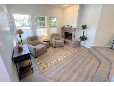 Comfortable living room featuring a brick fireplace, plush chairs, and natural light at 4760 S Wadsworth Blvd # F105, Littleton, CO 80123