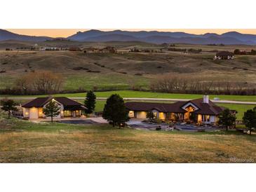 Expansive ranch style home showcasing beautiful landscape and illuminated front porch at 6330 Old Orchard Ln, Sedalia, CO 80135