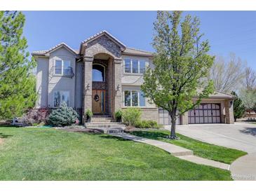 Beautiful two-story home with a manicured lawn, brick accents, and an inviting entrance with a large wooden door at 12825 W 81St Ave, Arvada, CO 80005