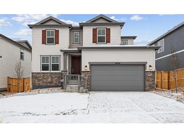 Charming two-story home featuring stone accents, attached two-car garage, and manicured front yard at 16634 W 93Rd Way, Arvada, CO 80007