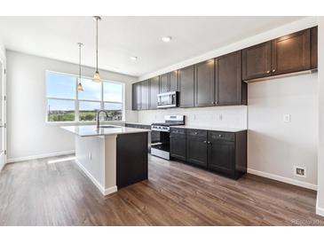 A modern kitchen with dark cabinets, stainless steel appliances and a white countertop island at 457 Interlocken Blvd # 101, Broomfield, CO 80021