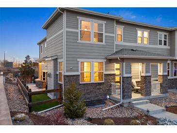 Charming gray townhome featuring stone accents, a cozy front porch, and a fenced-in side yard at 7257 S Millbrook Ct, Aurora, CO 80016
