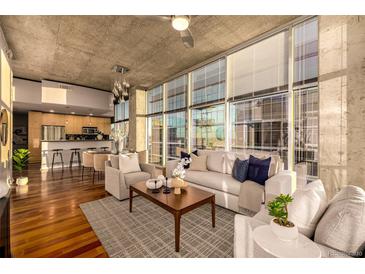 Bright living room featuring floor-to-ceiling windows, hardwood floors, and an open floor plan to the kitchen at 1700 Bassett St # 2117, Denver, CO 80202