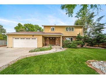 Inviting two-story home featuring an attached garage, well-maintained lawn, and mature trees at 2276 S Dover Way, Lakewood, CO 80227