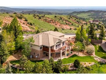 Beautiful exterior elevation of a luxury home featuring stone accents, tile roof, and a deck overlooking a mountain view at 16442 Rocky Point Ln, Morrison, CO 80465