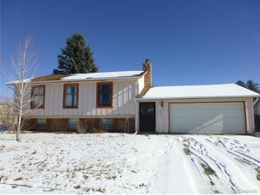 Ranch style home with attached garage, snow covered yard and mature tree at 4306 S Zinnia St, Morrison, CO 80465