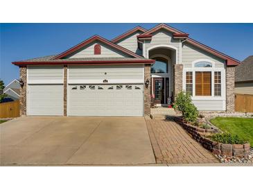 Charming two-story home featuring a spacious three-car garage and inviting brick-lined walkway at 9451 Desert Willow Trl, Highlands Ranch, CO 80129