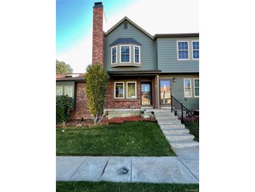 Green two-story townhome with brick accents and a manicured lawn at 17437 E Rice Cir # B, Aurora, CO 80015