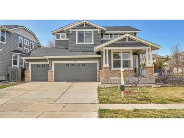 Beautiful two-story home boasts a three-car garage, gray siding, and a manicured lawn at 11845 Mobile St, Commerce City, CO 80022
