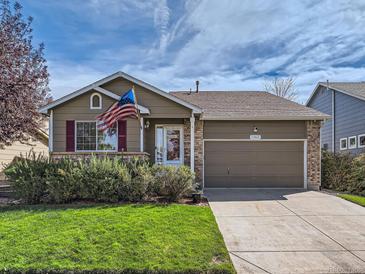 Brick ranch home with attached garage, landscaping, and American flag at 11462 Iola St, Commerce City, CO 80640