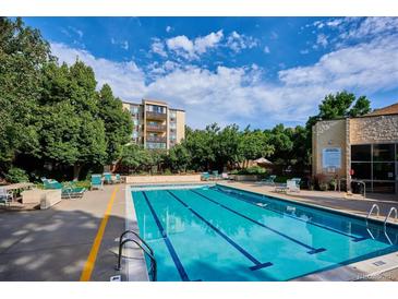 A refreshing community pool surrounded by lounging chairs and lush greenery under a bright, cloudy sky at 3465 S Poplar St # 506, Denver, CO 80224