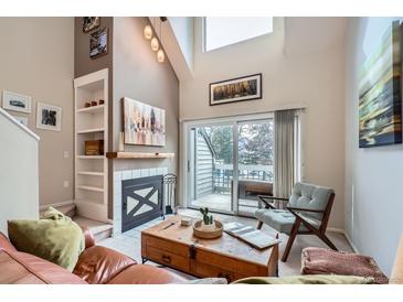 Bright living room with a fireplace, built-in shelves, and sliding glass door leading to a balcony at 3260 47Th St # 205A, Boulder, CO 80301