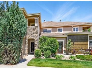 Charming townhome featuring a stone pillar, manicured lawn, and inviting outdoor seating area at 6292 Kilmer Loop # 201, Golden, CO 80403