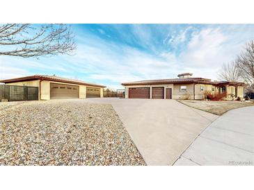 Expansive home featuring a long driveway leading to multiple garages, set against a blue sky at 3299 S Newcombe St, Lakewood, CO 80227
