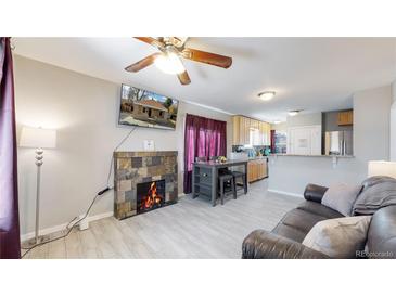 Inviting living room featuring a cozy fireplace, hardwood floors, and lots of natural light at 1621 Trenton St, Denver, CO 80220