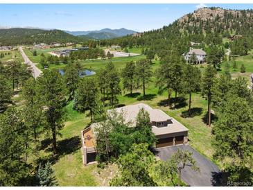 Stunning aerial view of a home nestled among lush greenery and mature trees on a large lot at 7197 Timbers Dr, Evergreen, CO 80439