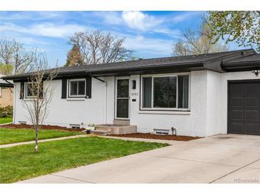 Charming single-story home with white brick exterior, well-manicured lawn and concrete driveway at 3103 W Bellewood Dr, Englewood, CO 80110