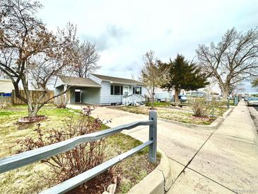 Charming one-story home with a carport, a well-manicured front yard, and a classic picket fence at 7901 Newport St, Commerce City, CO 80022