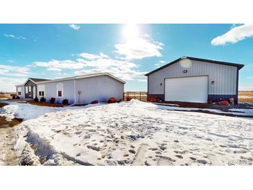 Gray manufactured home with detached garage on snowy lot at 43620 E 80Th Ave, Bennett, CO 80102