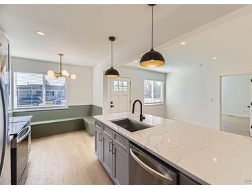 Bright kitchen features a center island with stainless steel appliances and modern pendant lighting at 3201 Albion St, Denver, CO 80207