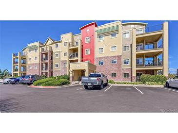 A modern condo building with balconies, brick accents, and ample parking on a clear, sunny day at 1044 Rockhurst Dr # 401, Highlands Ranch, CO 80129