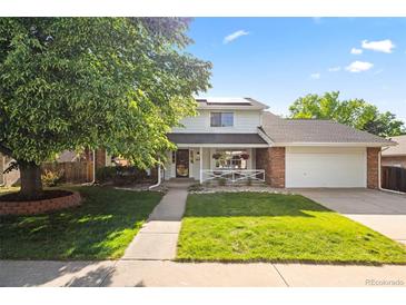 Charming two-story home with a well-manicured lawn, beautiful tree, and inviting front porch at 8035 S Garfield Way, Centennial, CO 80122