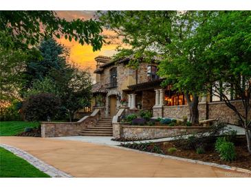 Stately stone home with meticulous landscaping, a winding driveway, and a sunset sky at 45 Charlou Cir, Cherry Hills Village, CO 80111